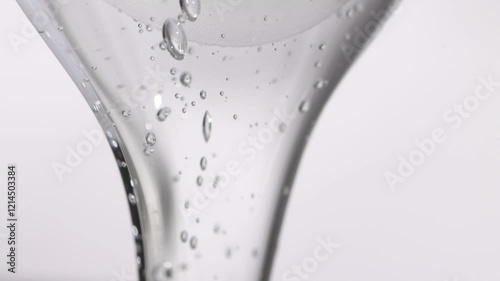 Hyaluronic acid, transparent liquid texture, flowing gel on a light background. Beauty product for skin moisturizing.