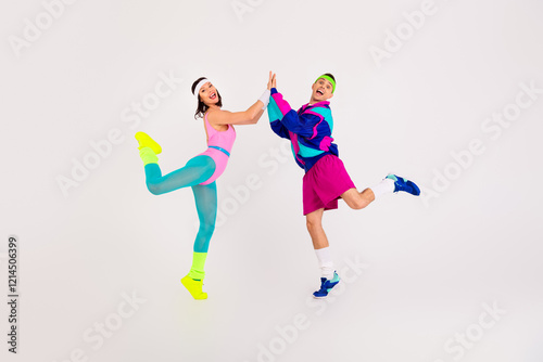 Energetic couple striking a retro aerobics pose with vibrant sportswear on a white background photo