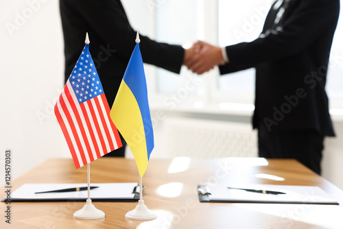 Diplomats shaking hands during meeting indoors, focus on flags of USA and Ukraine photo