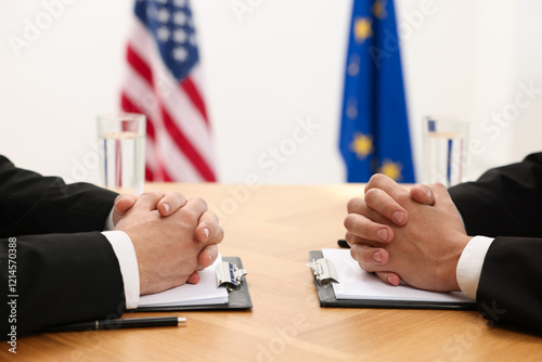 Diplomats negotiating during meeting at wooden table indoors, closeup photo