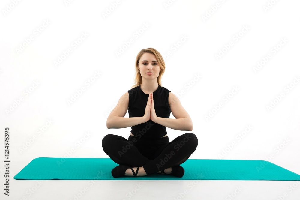 Fototapeta premium Yoga practitioner meditating in a cross-legged seated position on a green mat in a serene indoor setting