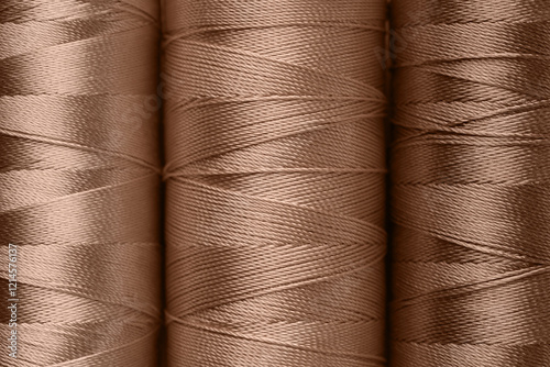 Sewing threads in mocha mousse shades, closeup. Trendy color of 2025 year