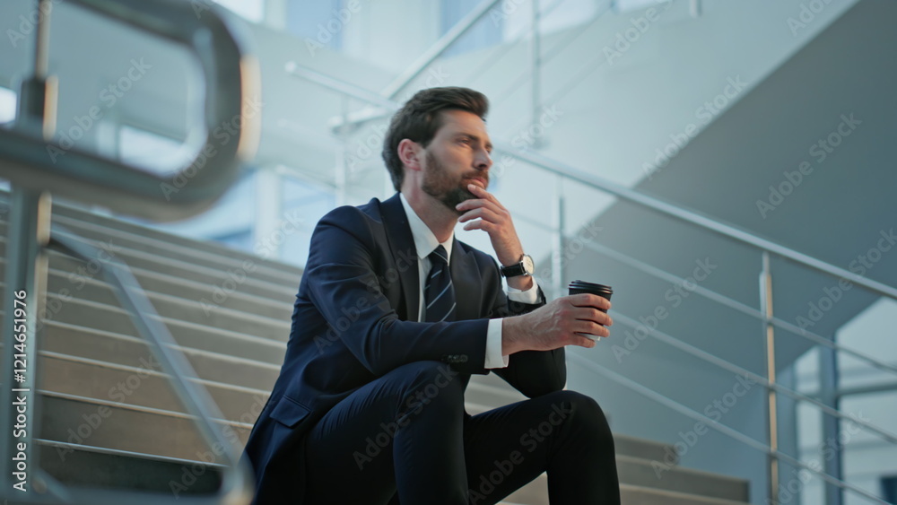 Professional man taking break with coffee on stairs office. Thoughtful executive Professional man taking break with coffee on stairs office. Thoughtful executive