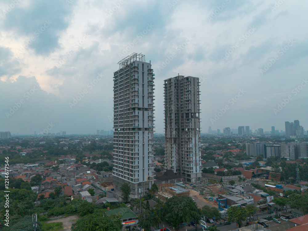 Obraz premium Stunning aerial shot of two modern high-rise buildings under construction against a cloudy sky. Perfect for real estate, architecture, and urban development projects.