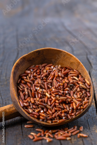 Heap of redrice and wooden spoon on vintage wood background photo