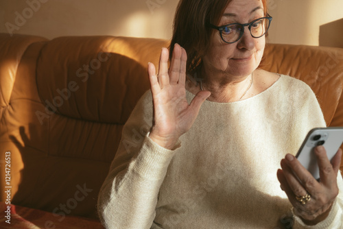 Wallpaper Mural Happy elderly senior mature woman is using mobile phone, online video call talk with waving hand, greeting her relatives and grandchildren.  Torontodigital.ca