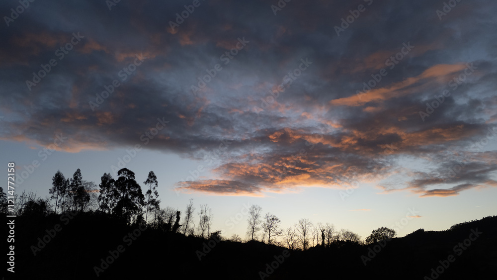 Sunlight illuminates the clouds as it gets dark creating a serene scene Sunlight illuminates the clouds as it gets dark creating a serene scene