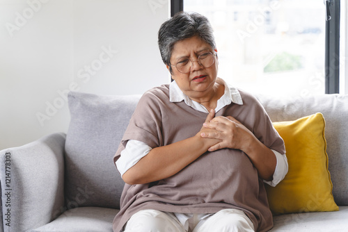Asian elderly grabbing her chest and feeling pain from heart attack suddenly at home.