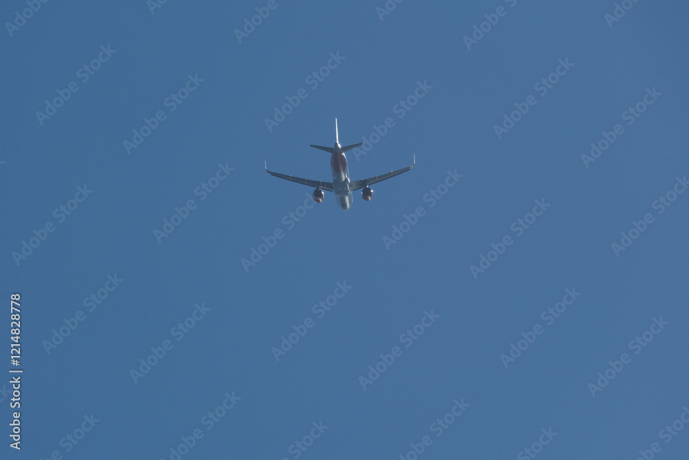 Jet airplane flying overhead in clear blue sky. Airplane in the blue sky. Jet airplane flying overhead in clear blue sky. Airplane in the blue sky.