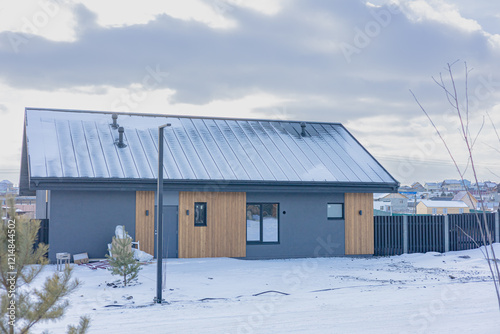 Wallpaper Mural Modern house with a gray exterior and a wooden accent wall. The roof is covered in snow, a black fence surrounds the house. The house is located in a residential area. Contemporary country house Torontodigital.ca