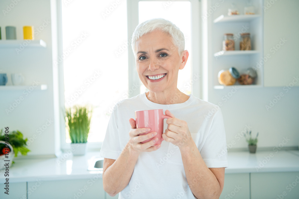Elderly woman enjoying a coffee break in the kitchen, showcasing leisure and happiness Elderly woman enjoying a coffee break in the kitchen, showcasing leisure and happiness