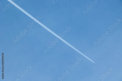 aereo di linea che vola lontano, in alto, nel cielo sereno e lascia la scia di condensa photo