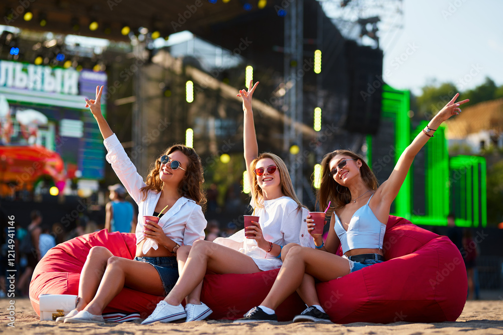 custom made wallpaper toronto digitalThree joyful women sit on red bean bag chairs, raising drinks at beachside music fest. Smiling friends celebrate with cocktails, enjoying summer festival vibes by the sea, casual party lifestyle.