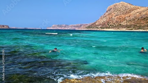 A lone swimmer enjoys the crystal-clear turquoise waters of Afrata Beach, surrounded by rocky cliffs and serene coastal scenery in Greece photo