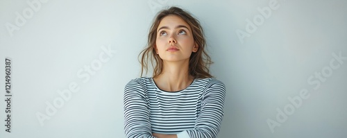 Young woman in casual attire looks thoughtfully upward against plain background. Appears thoughtful, likely facing difficult choice. Expression consideration, possible emotional challenge. Setting