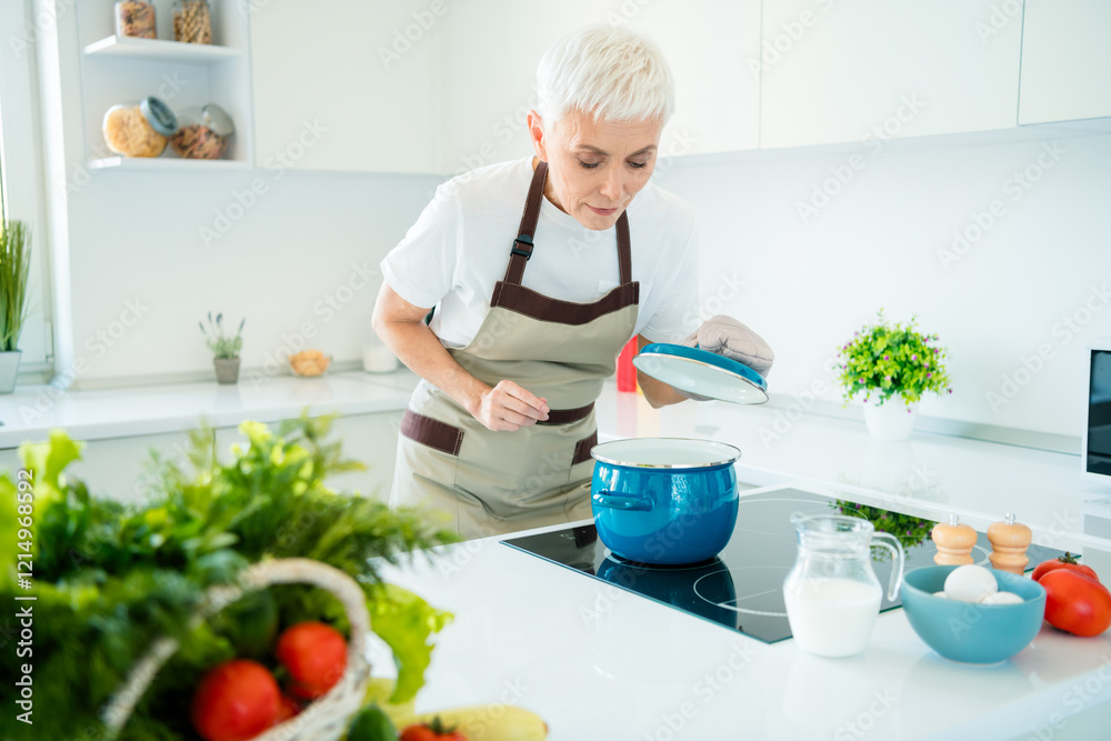 Elderly woman in an apron preparing a delicious meal in a bright modern kitchen with fresh ingredients