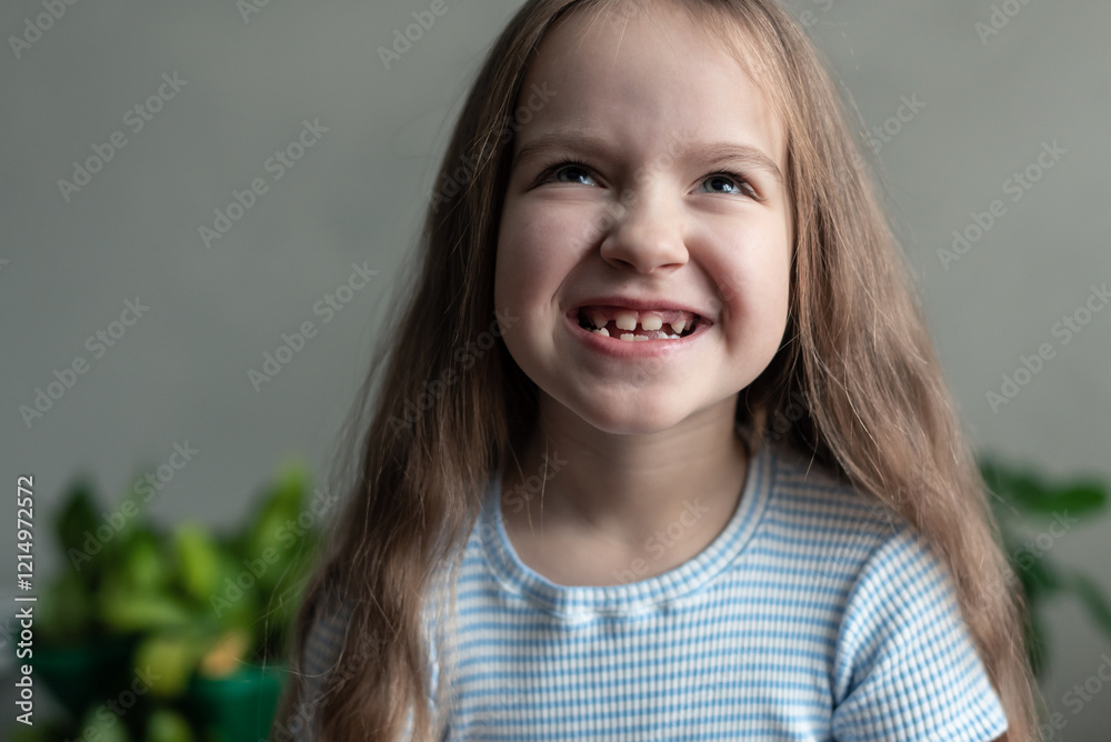 Caucasian young girl smiling with missing teeth in striped shirt indoors Caucasian young girl smiling with missing teeth in striped shirt indoors