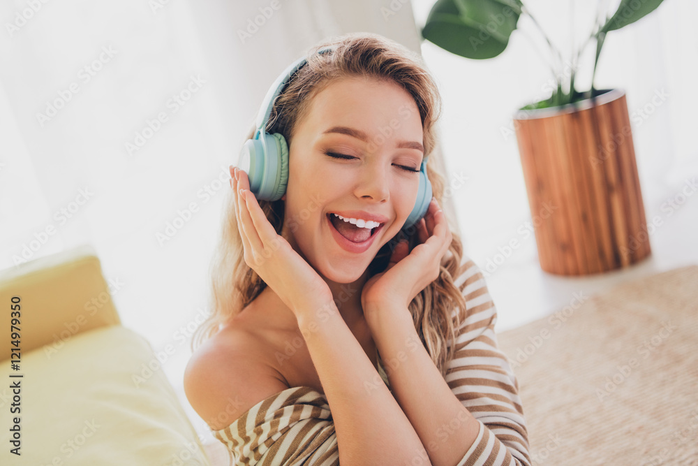 Young woman enjoying music with headphones while relaxing in a cozy living room on a peaceful weekend afternoon, dressed casually and radiating happiness. Young woman enjoying music with headphones while relaxing in a cozy living room on a peaceful weekend afternoon, dressed casually and radiating happiness.