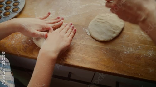 Mother and daughter pressing dough with hands on wooden surface. Female and child flattening dough together during cooking preparation. Lady and girl working side by side shaping dough for meal