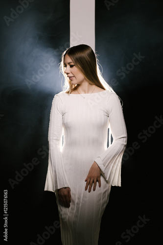 Portrait of a woman in a studio with professional lighting in a white long dress, soft focus