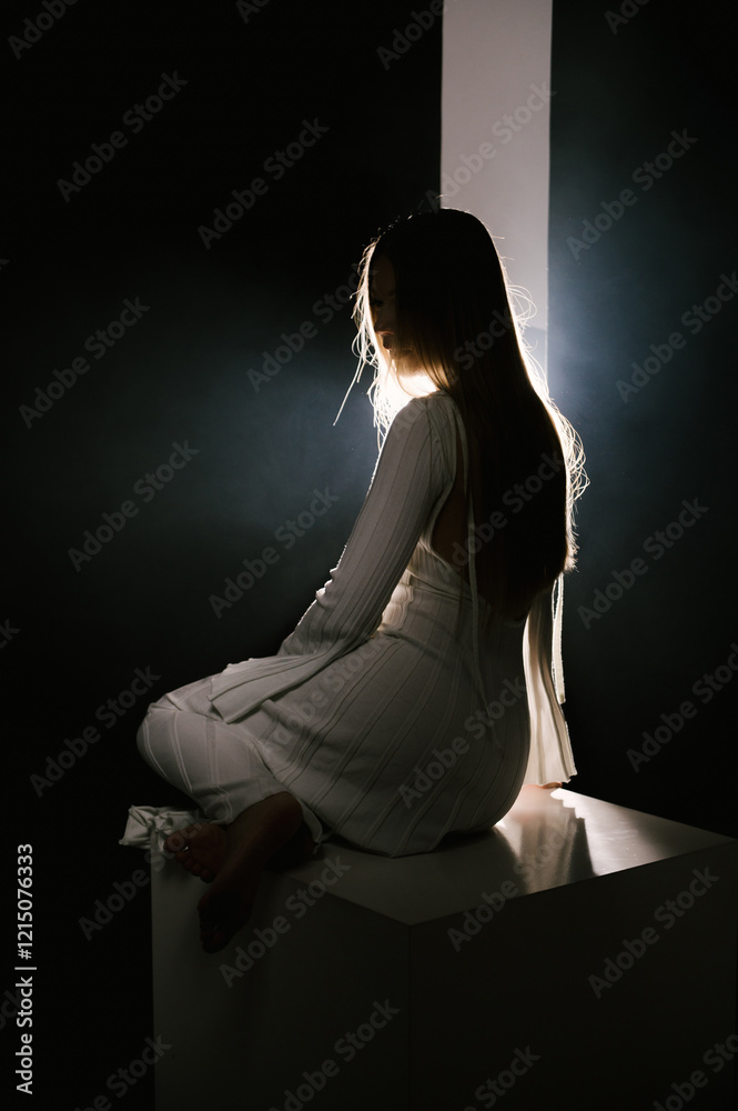 Portrait of a woman in a studio with professional lighting in a white long dress, soft focus