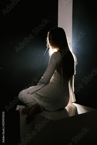 Portrait of a woman in a studio with professional lighting in a white long dress, soft focus