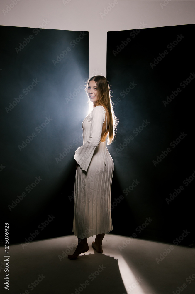Portrait of a woman in a studio with professional lighting in a white long dress, soft focus