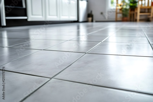 Low angle view capturing a shiny gray tiled kitchen floor, reflecting modern kitchen furniture and creating a clean, stylish atmosphere