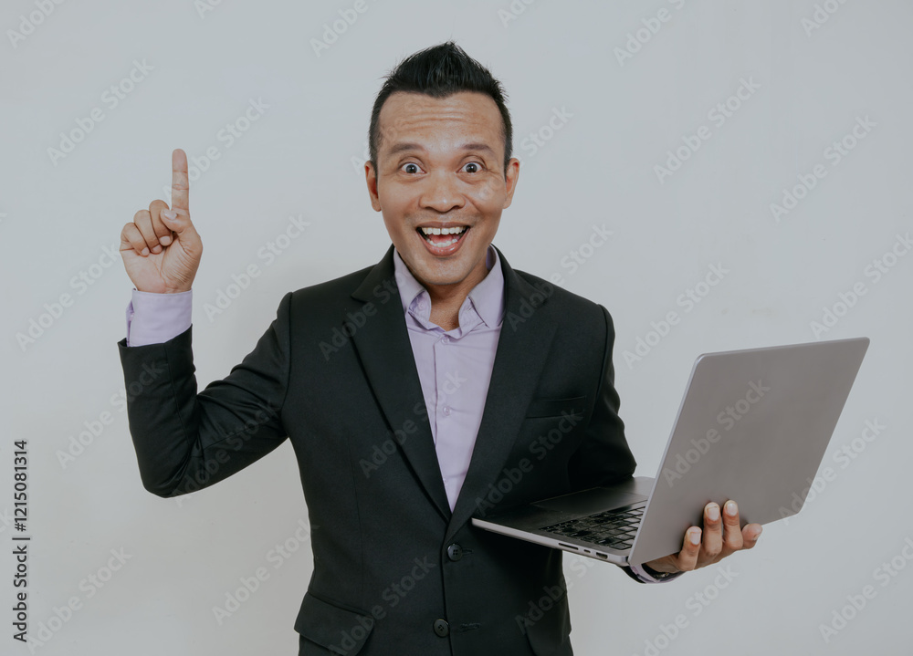 Asian business man wearing formal black suit smiling happy and pointing finger up while holding his laptop. Isolated over white background. Asian business man wearing formal black suit smiling happy and pointing finger up while holding his laptop. Isolated over white background.