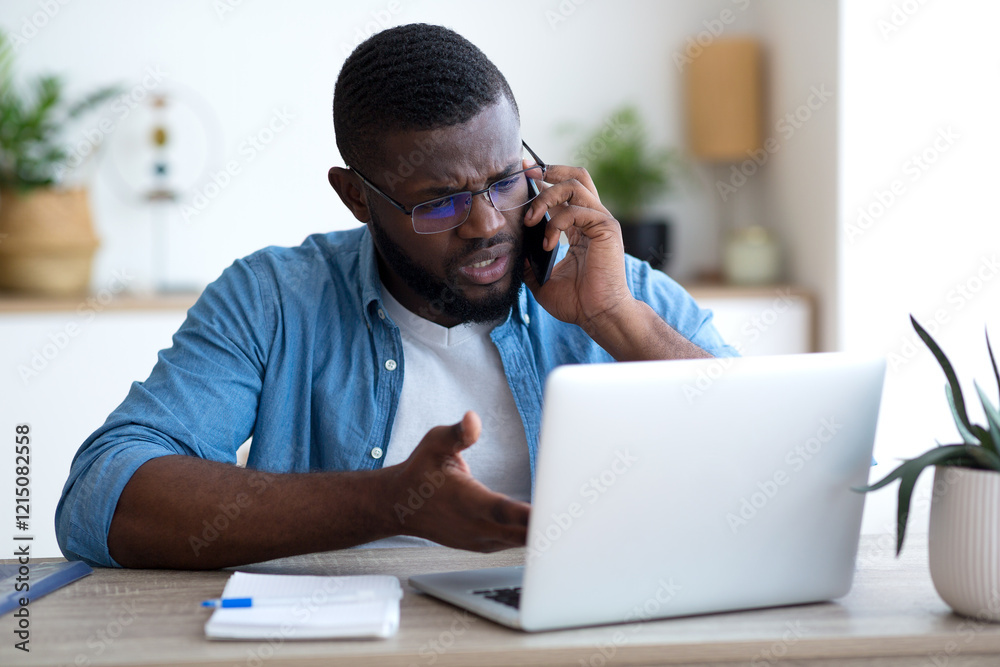 Obraz premium Failure and crisis concept. Upset african american employee getting bad news on phone while sitting at his workplace in office, copy space. High quality photo