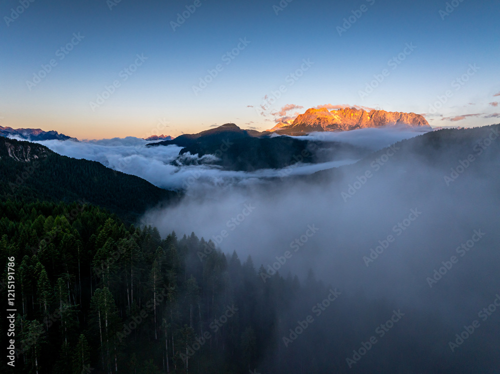 Scenic aerial morning view of misty valleys and forested landscapes in the Dolomites, with Antelao and Cridola peaks in the background. Captured near Danta village, Italy. Hiking in Dolomites.