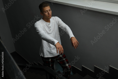 Young man suffering from sleepwalking on stairs indoors photo