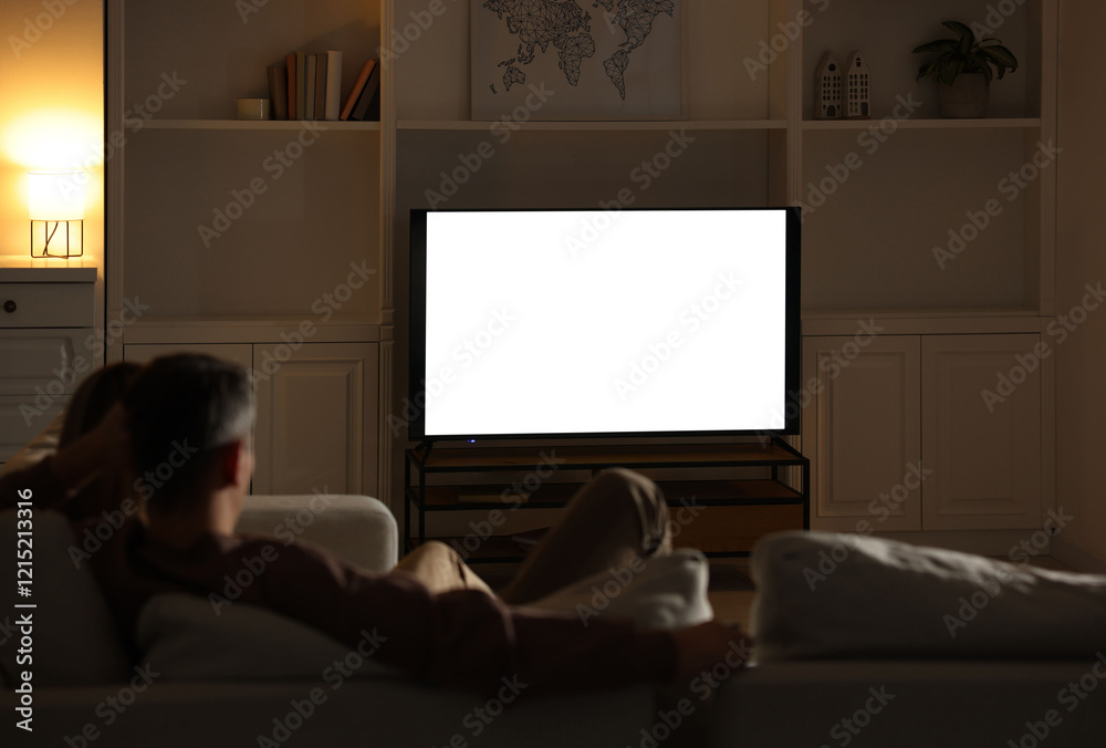 Couple watching TV on sofa at home in evening, back view Couple watching TV on sofa at home in evening, back view