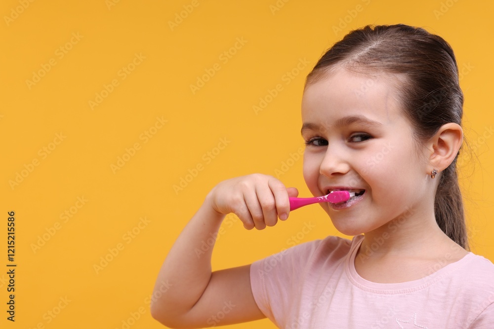 Cute girl brushing her teeth on orange background, space for text Cute girl brushing her teeth on orange background, space for text