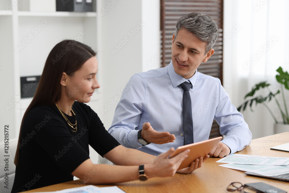 Coworkers with tablet working at table in office Coworkers with tablet working at table in office