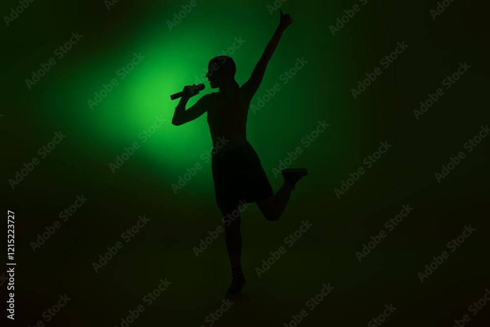 Silhouette of woman singing on dark background with green light Silhouette of woman singing on dark background with green light