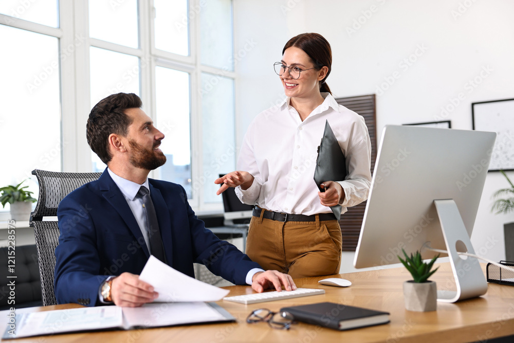 Colleagues working together at desk in office Colleagues working together at desk in office