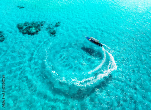 Fototapeta Naklejka Na Ścianę i Meble -  Aerial view of the speed boat in clear azure water on summer sunny day. Top drone view of fast floating yacht in ocean ocean. Travel in Maldives. Tropical seascape with motorboat on blue sea. Travel