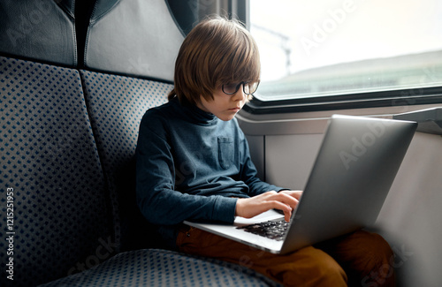 Focused Boy Typing on Laptop in Train. photo
