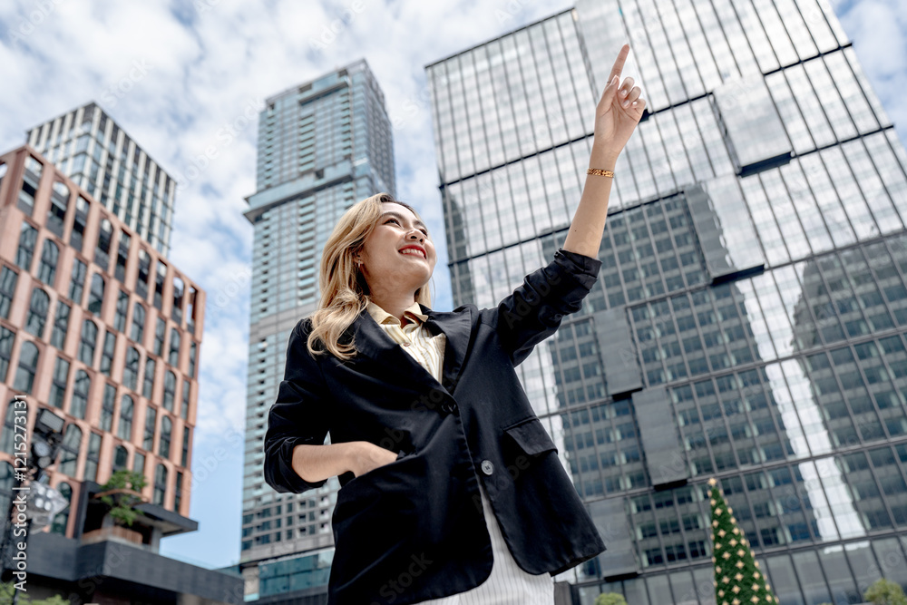 Low angle view of a smiling professional woman in a cityscape, reaching out with confidence. A powerful representation of success, determination, and urban professional lifestyle. Low angle view of a smiling professional woman in a cityscape, reaching out with confidence. A powerful representation of success, determination, and urban professional lifestyle.