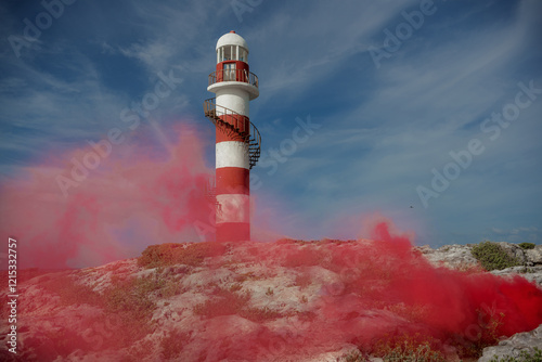 A lighthouse on a rocky coast in Cancun with a red smoke screen. Mexico. photo