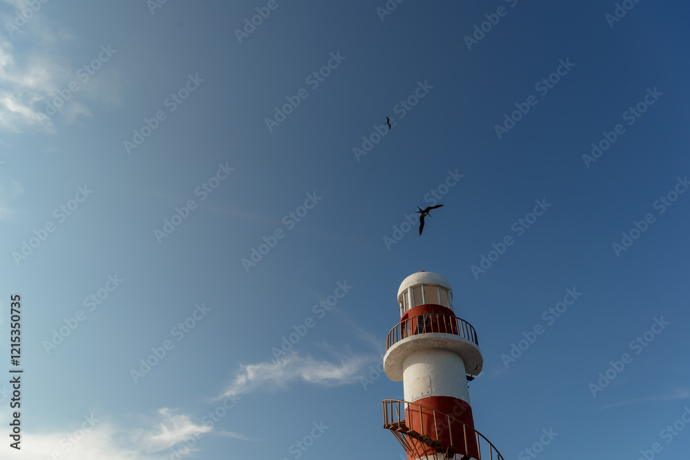 Top of a white-red lighthouse against a blue sky with an airplane. Top of a white-red lighthouse against a blue sky with an airplane.