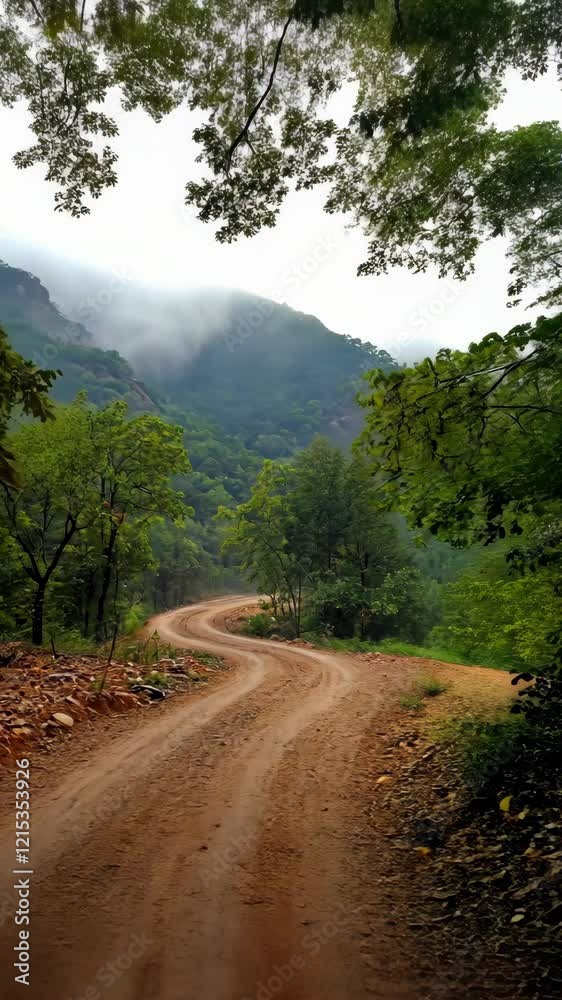 Winding dirt road through lush green hills on a cloudy afternoon in a mountainous region Winding dirt road through lush green hills on a cloudy afternoon in a mountainous region
