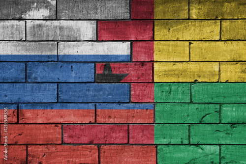 colourful painted big flag of russia and flag of guinea bissau on a massive old brick wall background. concept