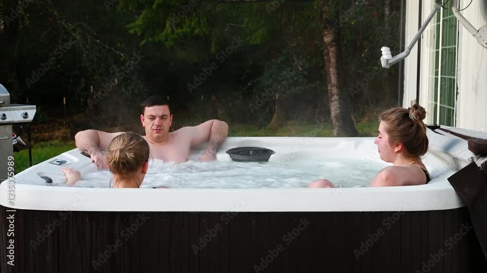 Friends on a weekend getaway to a house in the countryside relax in the brand new backyard jacuzzi in the garden.