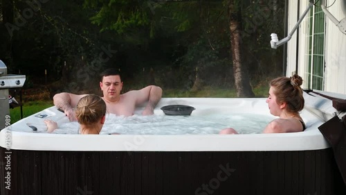 Friends on a weekend getaway to a house in the countryside relax in the brand new backyard jacuzzi in the garden.
