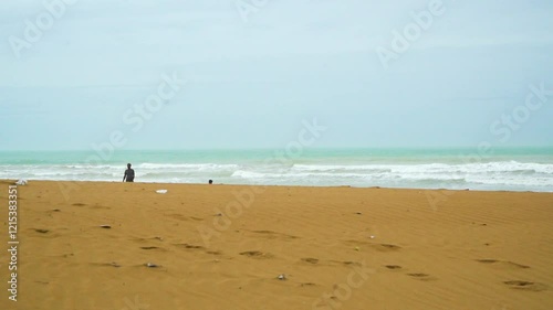 Static drone shot of the ocean with calm waves reaching the shore of a white sand beach on a tropical island of Pakistan during bright sunny day