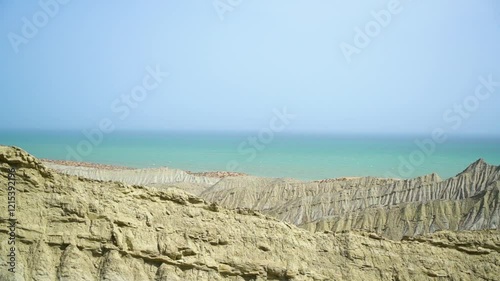 Static drone shot of the ocean with calm waves reaching the shore of a white sand beach on a tropical island of Pakistan during bright sunny day