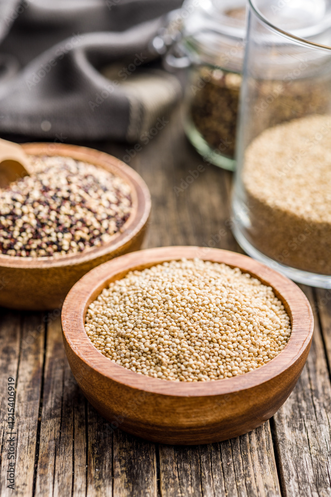 Mixed uncooked quinoa seeds in bowl on wooden table. Mixed uncooked quinoa seeds in bowl on wooden table.