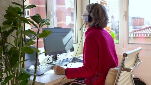 Senior woman working from home office using headset